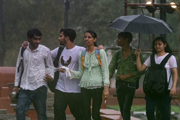 Youngsters walk along a road near India Gate during the Saturday's rain in New Delhi. (PTI)