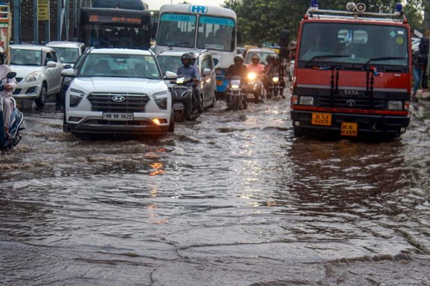 Vehicles move through a waterlogged street following Saturday's heavy monsoon rain near Rajiv Chowk in Gurugram on Saturday. (PTI)