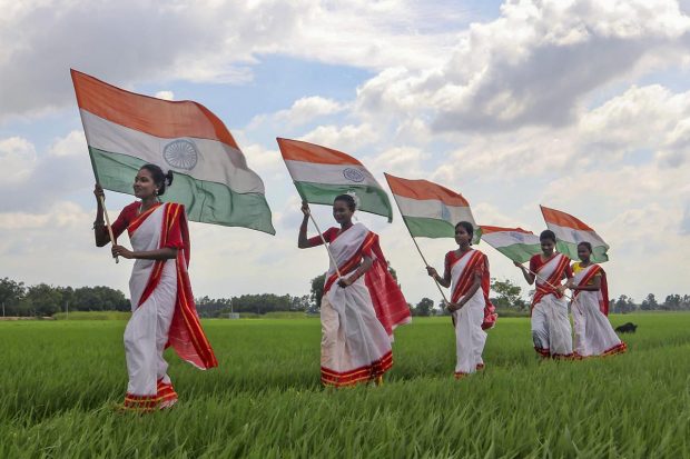 Young women pose holding the national flag walk through a paddy field ahead of the 75th Independence Day, in South Dinajpur. (PTI Photo)