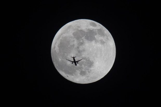 An aircraft flies past the full moon over Basra, Iraq. (AP Photo)