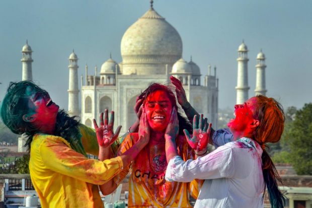 Young women celebrate Holi at the Taj Mahal complex, in Agra. (PTI Photo)