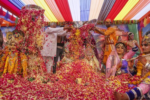 People shower flower petals on artists dressed as Lord Krishna and Radha during 'Lathmaar Holi' celebrations at Krishna Janambhoomi Temple, in Mathura. (PTI Photo)