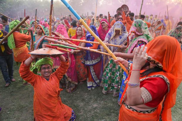 A woman beats a man with sticks as they play 'Lathmaar Holi' at Krishna Janambhoomi Temple, in Mathura. (PTI Photo)