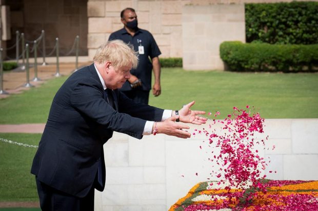 British Prime Minister Boris Johnson showers flower petals as he pays tribute to Mahatma Gandhi at Rajghat in New Delhi. (Reuters Photo)