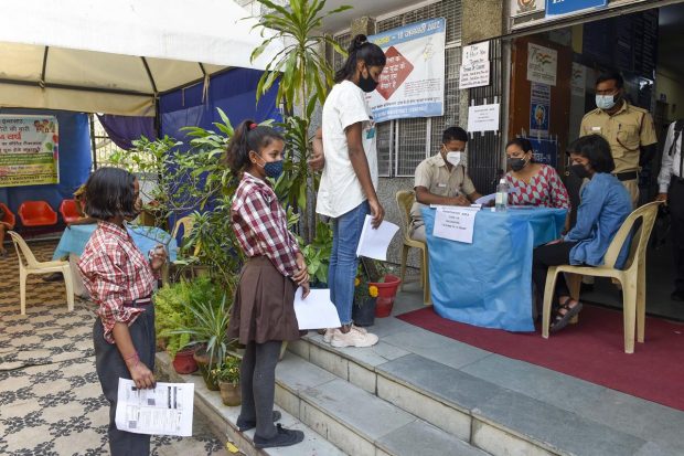 Students in the age group of 12-14 years, holding their identification cards wait in a queue to receive a dose of Covid-19 vaccine at a vaccination centre, in New Delhi. (PTI Photo)