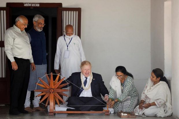 Boris Johnson spins cotton on a wheel during his visit to Gandhi Ashram in Ahmedabad. (Reuters Photo)