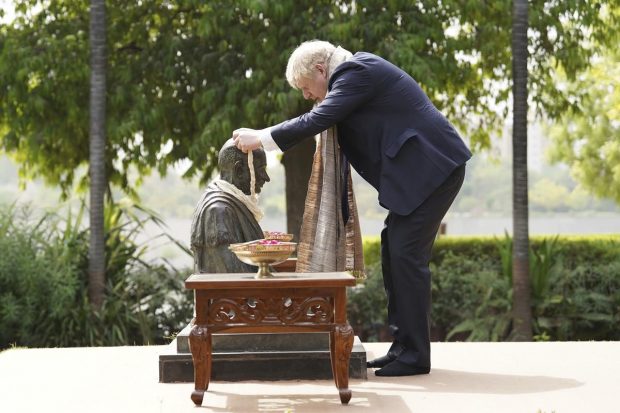 Boris Johnson places a garland around the neck of a statue of Mahatma Gandhi at his Sabarmati Ashram in Ahmedabad during a cultural tour as part of his two-day visit to India. (AP Photo)