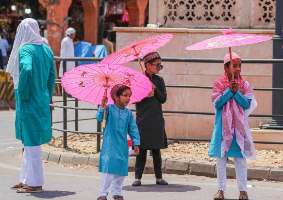 Jaipur: Children use umbrellas to protect themselves from heat as they arrives to offer prayers on the last Friday of the holy month of Ramadan, at Jama Masjid in Jaipur. (PTI Photo)