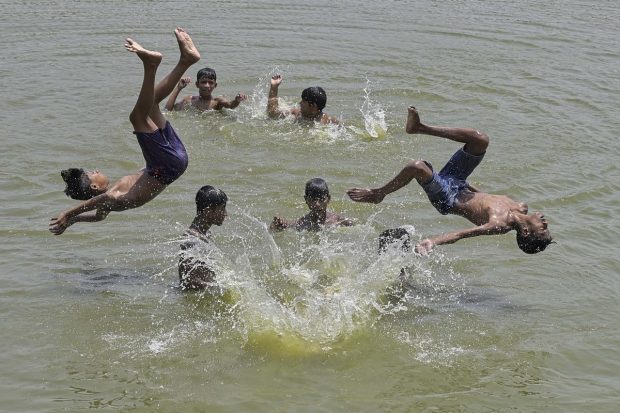 Boys play in a waterbody to cool themselves on a hot summer day in Nadia. (PTI Photo)